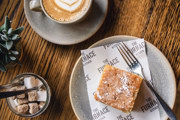 Straight down view of a piece of lemon drizzle cake on a grey ceramic plate with a piece of Furnace Kitchen branded greaseproof paper.